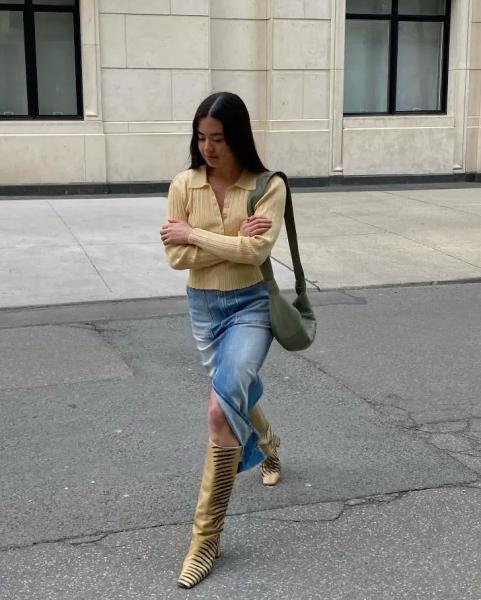 Девушка в джинсовой юбке миди, желтом джемпере и высоких сапогах